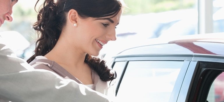 Car dealer pointing the interior of a car